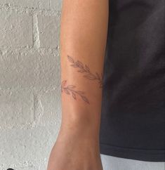 a woman's arm with a small branch tattoo on the left side of her arm