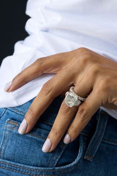 a woman's hand with a ring on her left wrist, wearing jeans and a white t - shirt