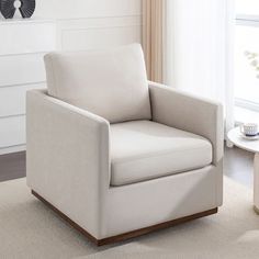 a living room with a white chair and coffee table in front of a large window