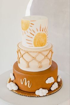 a three tiered cake with white frosting and yellow decorations on top, sitting on a table