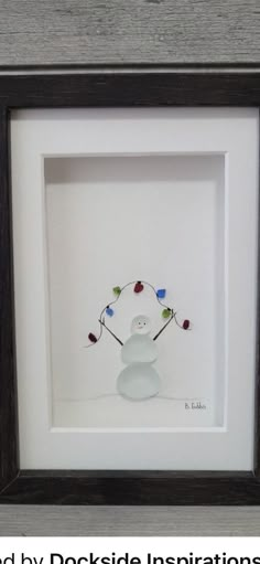 a small white snowman in a black frame