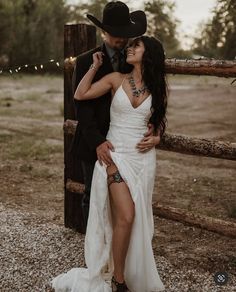 a woman in a white dress and cowboy hat standing next to a man wearing a black suit