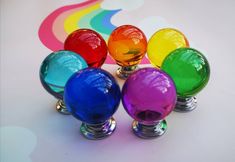 four colorful glass knobs on top of each other in front of a rainbow background