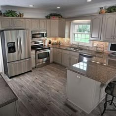 a large kitchen with stainless steel appliances and wood flooring is pictured in this image