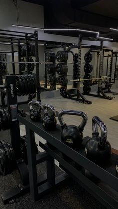 a gym filled with black kettles and exercise equipment on top of a wooden floor