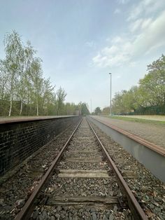 an empty train track with no cars on it and trees in the backround