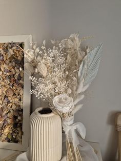 there is a vase with flowers in it on the table next to a framed photograph