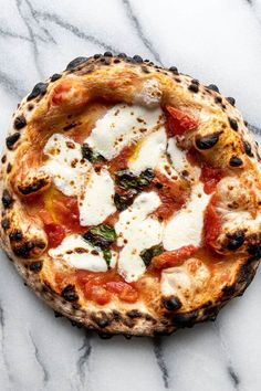 a pizza sitting on top of a white marble counter covered in cheese and toppings