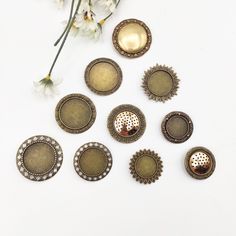 six antique style buttons and some flowers on a white surface