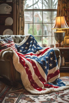 an american flag blanket is draped over a couch in front of a window with a lamp