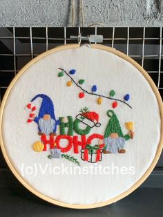 an embroidered hoop hanging from a wire with the words ho ho ho and gnomes on it