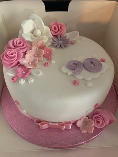 a white cake with pink and purple flowers on it's side in a box