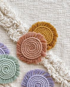 three different colored pieces of yarn on a white surface with fringes and circles in the middle