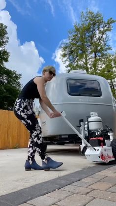 a man is using a lawn mower to clean the driveway outside his trailer house