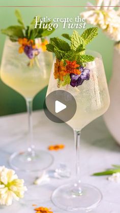 two glasses filled with drinks and garnished with flowers on the table next to each other