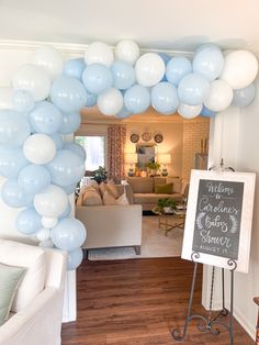 a living room filled with balloons and a chalkboard sign in the middle of it