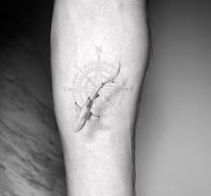 a black and white photo of a person's leg with a compass tattoo on it