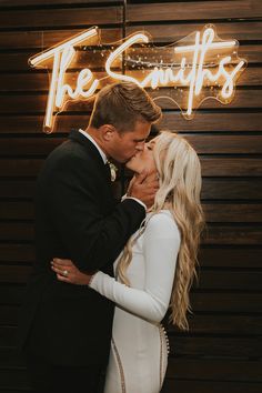 a bride and groom kissing in front of the neon sign for the scufffs