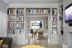 a living room filled with lots of furniture and bookshelves next to a flat screen tv