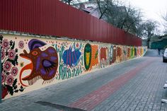 a wall with many different designs painted on it's side next to a street