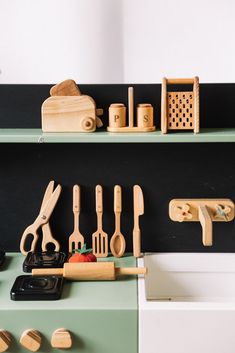 wooden utensils and other kitchen accessories are arranged on the green shelf above the sink