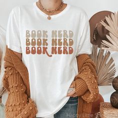 "Book Nerd Shirt, Bookish Shirt, Reading Shirt, Poet Shirt, Literature Shirt, Librarian Shirt, Retro Gift, Aesthetic Clothes, Indie T Shirt These shirts are so soft and comfortable! They are also super versatile. Pair them with cardigans, jackets, leggings, or jeans.  You can also roll up the sleeves and tie a knot on the side. The possibilities are endless! For an oversized look, order a size or two up from your normal size. Materials: 100% Airlume combed and ringspun cotton (fiber content may vary for different colors) Sizing: These are unisex shirts so they fit a bit looser than women's t-shirts. Please refer to the size chart image in the listing. I recommend taking one of your favorite tees and measuring it while it's laying flat. Our size chart measurements are taken while lying flat Indie T Shirts, Literature Shirt, Book Nerd Shirts, Nerd Shirt, Poet Shirt, Gift Aesthetic, Kindness Shirt, Librarian Shirt, Coffee Tees