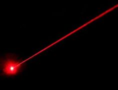 a red laser is visible in the dark sky