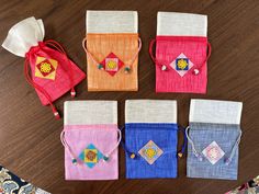 four small pouch bags sitting on top of a wooden table next to a bag filled with beads