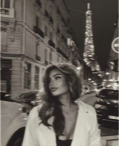 black and white photograph of woman in front of the eiffel tower at night