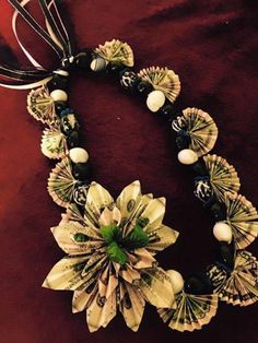 a necklace with flowers and pearls on it sitting on a red velvet surface next to a pair of scissors