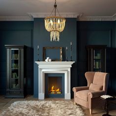 a living room filled with furniture and a fire place under a chandelier hanging from the ceiling