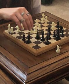 a person playing chess on a wooden table