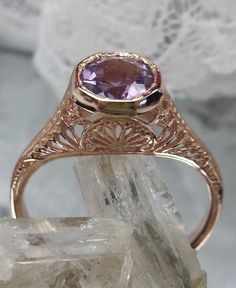 Natural Purple Amethyst Ring Dandelion Design #205 Made To Order This exquisite ring is a beautiful replica of Edwardian wedding jewelry, crafted with intricate filigree detail. The center stone is a .52ct natural purple amethyst, measuring 6mm in diameter. The ring is made with a combination of rose gold plating and sterling silver, stamped with the mark 925 on the inner shank. The rose gold and sterling silver filigree setting truly showcases the stunning craftsmanship of this piece. This orna Amethyst Rings With Intricate Design For Wedding, Gold Amethyst Ring For Wedding, Gold Amethyst Ring For Wedding, Round Cut, Gold Amethyst Ring With Center Stone For Wedding, Classic Lavender Jewelry For Wedding, Oval Amethyst Filigree Ring For Wedding, Purple Diamond Cut Jewelry For Wedding, Elegant Filigree Amethyst Ring For Wedding, Elegant Amethyst Filigree Ring For Wedding