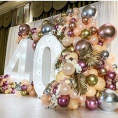 the number forty is surrounded by balloons and flowers in gold, silver, and pink colors