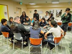 a group of people sitting around a table playing cards