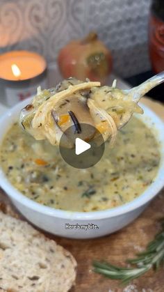 a spoon full of soup sitting on top of a table next to bread and candles