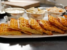 some waffles are on a white plate with other bowls