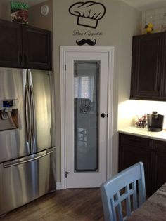 a stainless steel refrigerator in a kitchen next to a wall sticker with a chef's hat on it