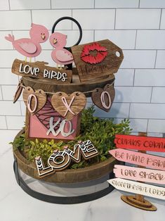 there are some wooden signs on top of a planter with flowers and birds in it