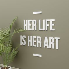 a plant in a pot next to a sign that says her life is her art