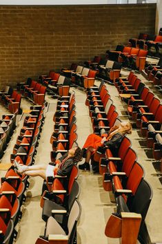 a woman laying on the floor in an auditorium filled with red chairs and empty seats