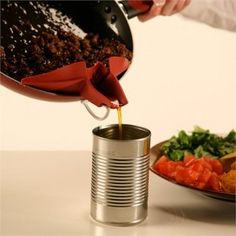 a person pours sauce over a plate of food on a white counter top with a red can