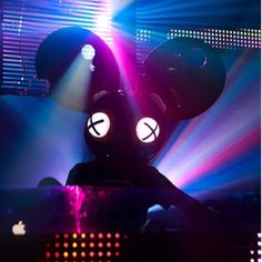 a mickey mouse dj performing in front of colorful lights