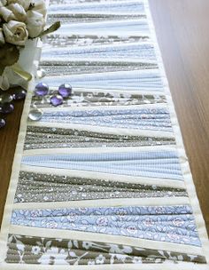 the table runner has flowers on it and is next to a vase with white roses