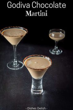 two glasses filled with chocolate martinis sitting on top of a black table next to each other