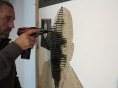 a man is using a drill to fix a piece of art on the wall with his hands