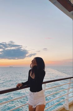 a woman standing on the side of a boat looking at the ocean