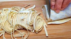 a person is cutting up some food on a wooden table