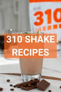 a glass filled with liquid and chocolate chips on top of a white table next to an orange sign