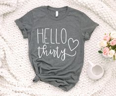 a t - shirt that says hello things on it next to flowers and a cup